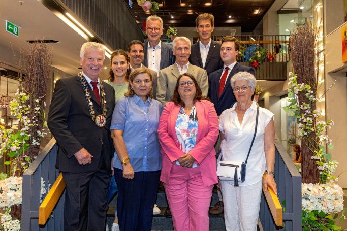 Gruppenfoto mit Personen in formeller Kleidung, lächelnd auf einer Treppe.
