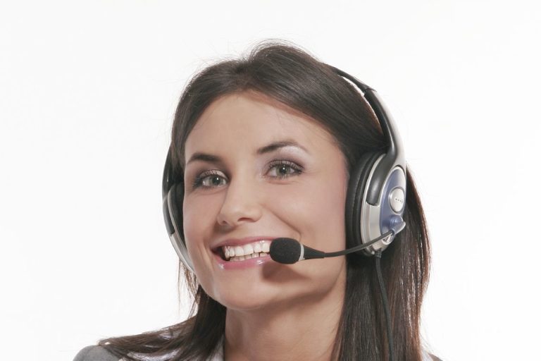 Frau mit Headset und Mikrofon, lächelt freundlich in die Kamera.
