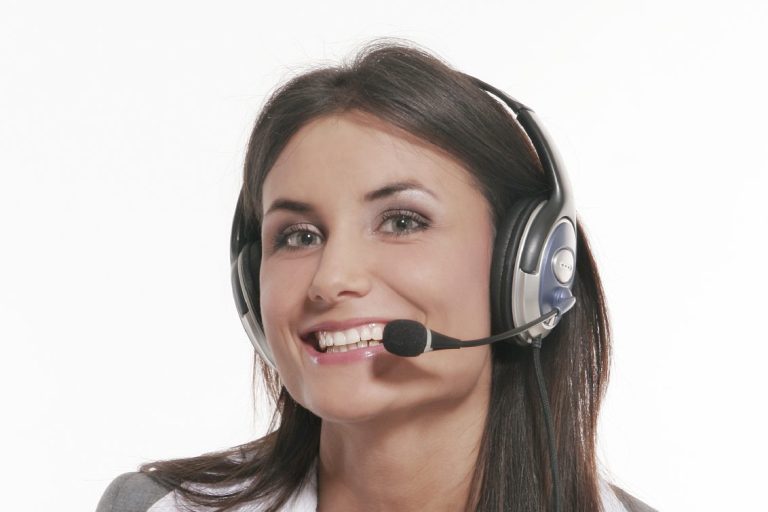 Junge Frau mit Headset lächelt freundlich in die Kamera.
