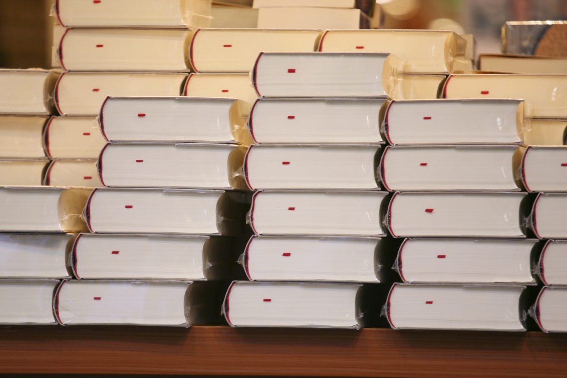 Gestapelte Bücher mit beige Umschlägen, Rücken sichtbar, in mehreren Reihen.