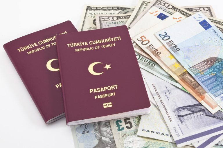 Zwei türkische Reisepässe auf einem Haufen verschiedener Währungen.