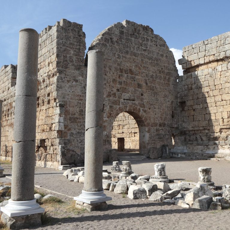 Ruin einer antiken Stadt mit durchscheinenden Säulen und einem großen Eingang.