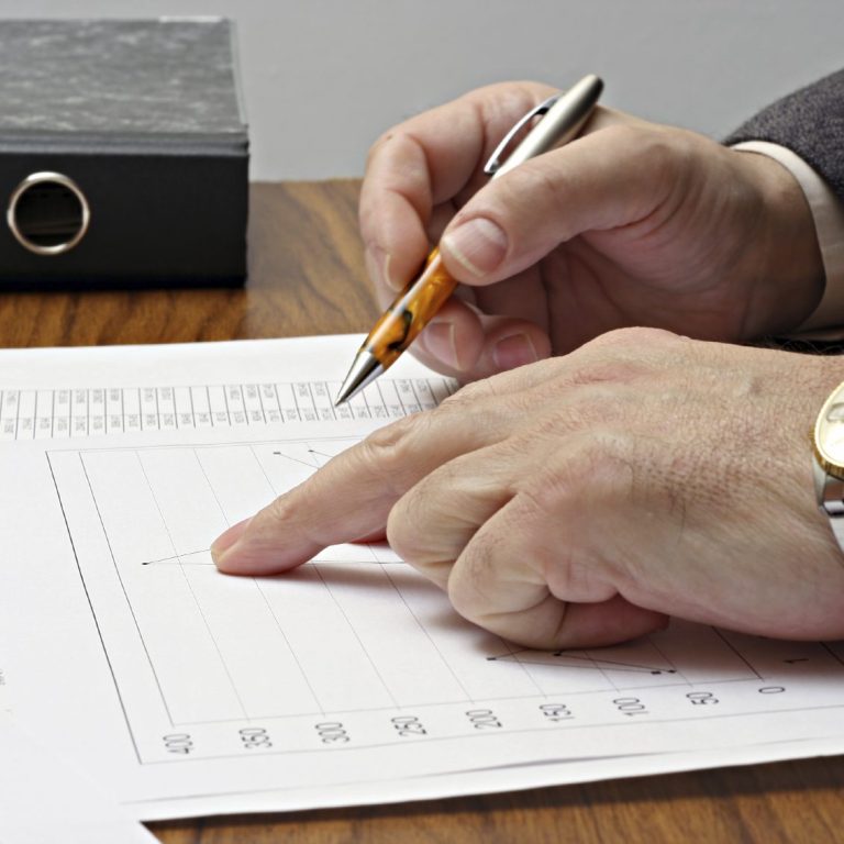 Eine Hand zeigt auf ein Diagramm, während die andere einen Stift hält.