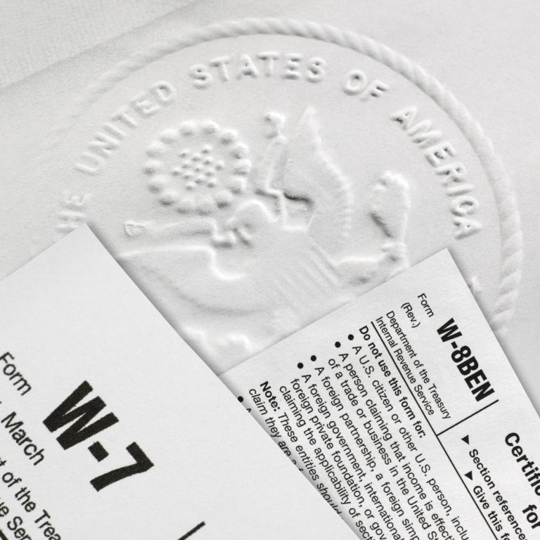Dokumente der US-Steuerbehörde mit Wappen und Formularen W-7 und W-8BEN.