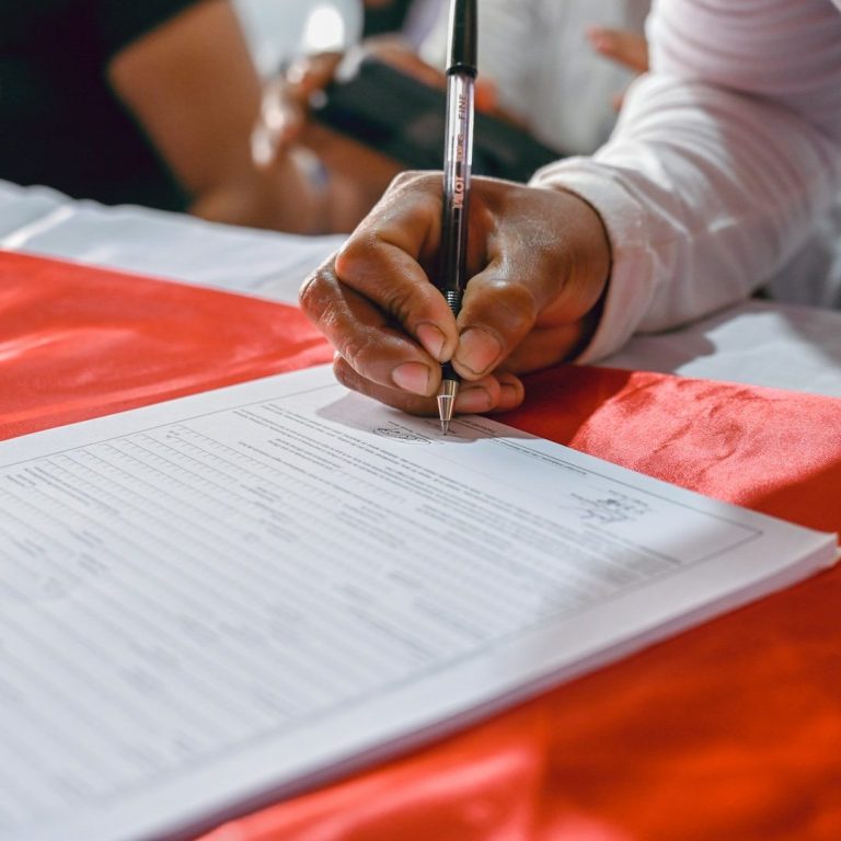 Hand unterschreibt offizielles Formular – Symbolbild für beglaubigte Übersetzungen juristischer und behördlicher Dokumente Türkisch⇌ Deutsch