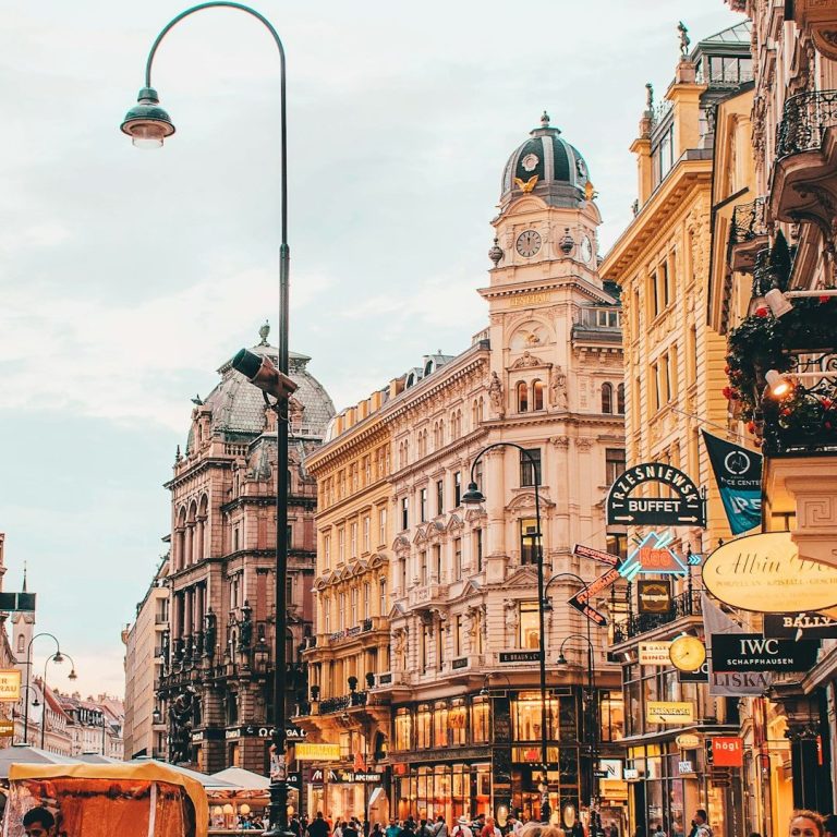 Straße mit historischen Gebäuden und Laternen im Abendlicht.
