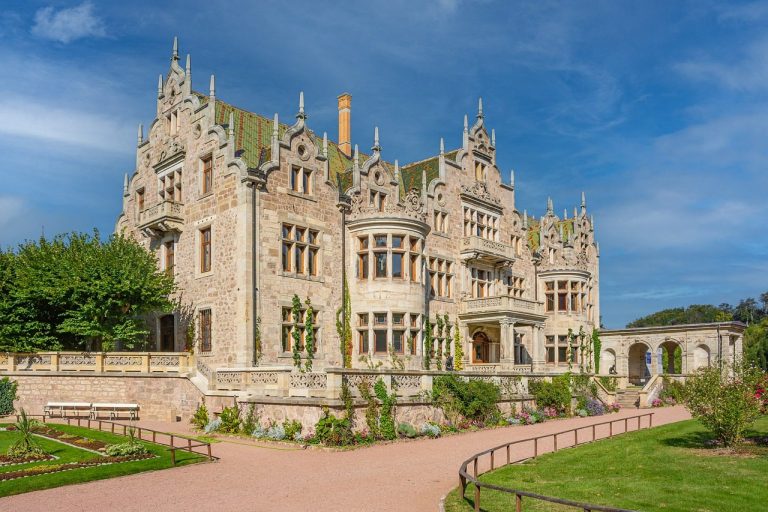 Historisches Schloss mit aufwendiger Fassade und grünen Gartenanlagen.