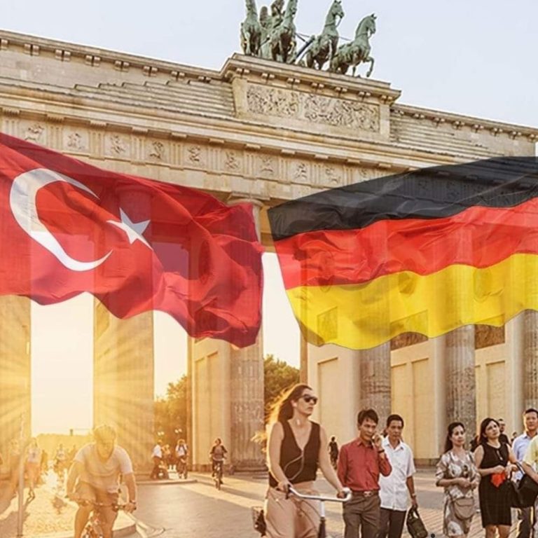 Menschen stehen vor dem Brandenburger Tor, während türkische und deutsche Fahnen wehen.