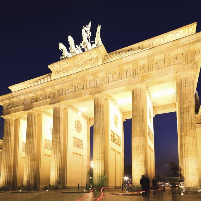 Das Brandenburger Tor bei Nacht, beleuchtet mit majestätischen Säulen und Skulpturen.