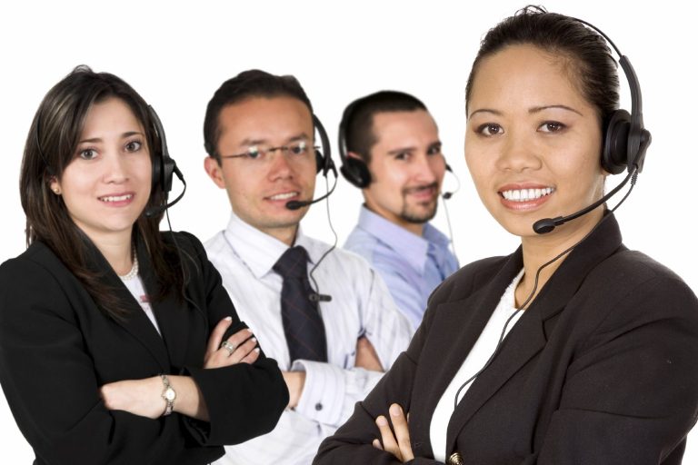 Vier Menschen mit Headsets, die lächeln und freundlich in die Kamera schauen.