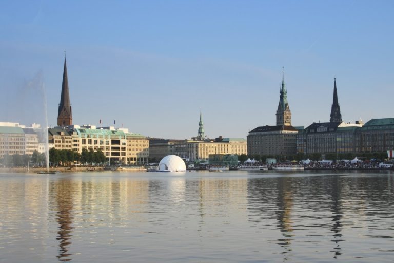 Blick auf die Hamburger Innenstadt mit vielen Türmen und einem ruhigen Wasserlauf.