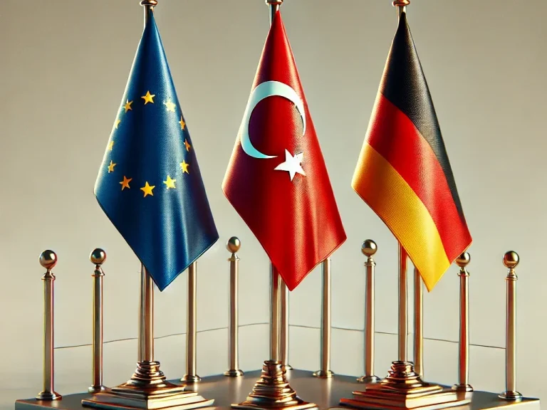 Drei Flaggen: EU, Türkei und Deutschland, aufgestellt vor einem neutralen Hintergrund.