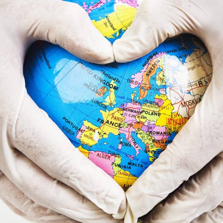 Hände formen ein Herz um eine Weltkugel mit Europa-Karte.
