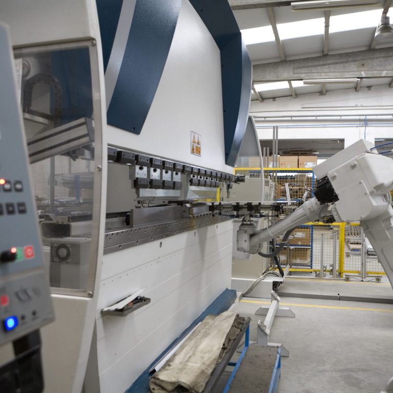 Schnellpresse in einer Produktionshalle mit automatisiertem Bedienarm.