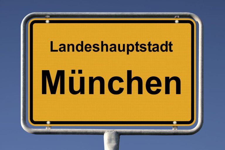Schild mit der Aufschrift „Landeshauptstadt München“ auf gelbem Hintergrund.