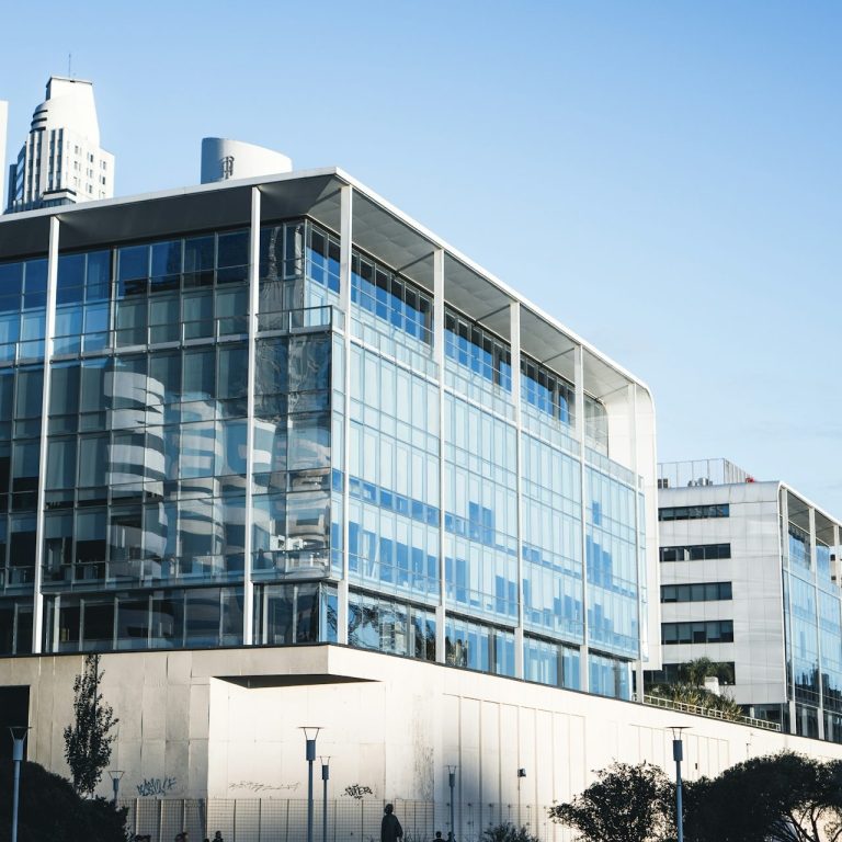 Moderne Gläserne Bürogebäude mit klaren Linien und blauen Himmel im Hintergrund.