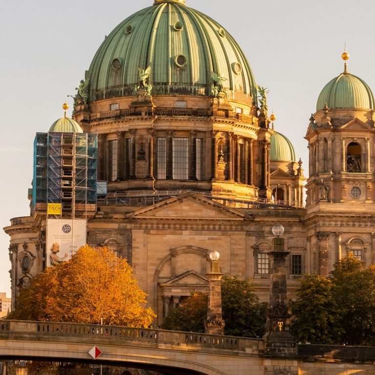 Berliner Dom mit grünem Kuppeldach und orangefarbenem Herbstlaub im Vordergrund.