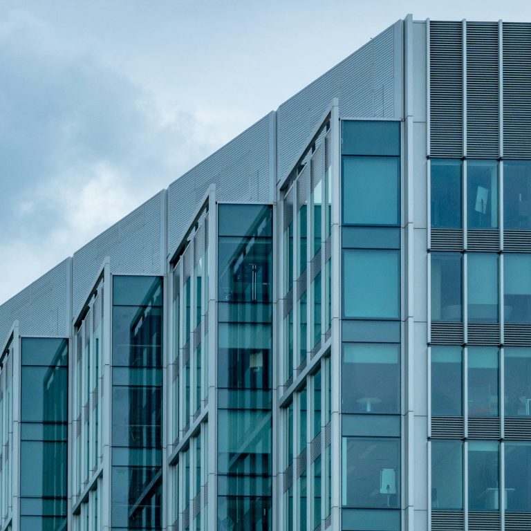 Moderne Gebäudefassade mit Glasfenstern und markanter Dachlinie.