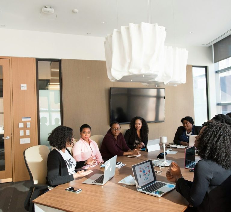 Mehrere Personen in einem modernen Besprechungsraum bei einem Business-Meeting mit Laptops – Symbol für Dolmetschen in Konferenzen 