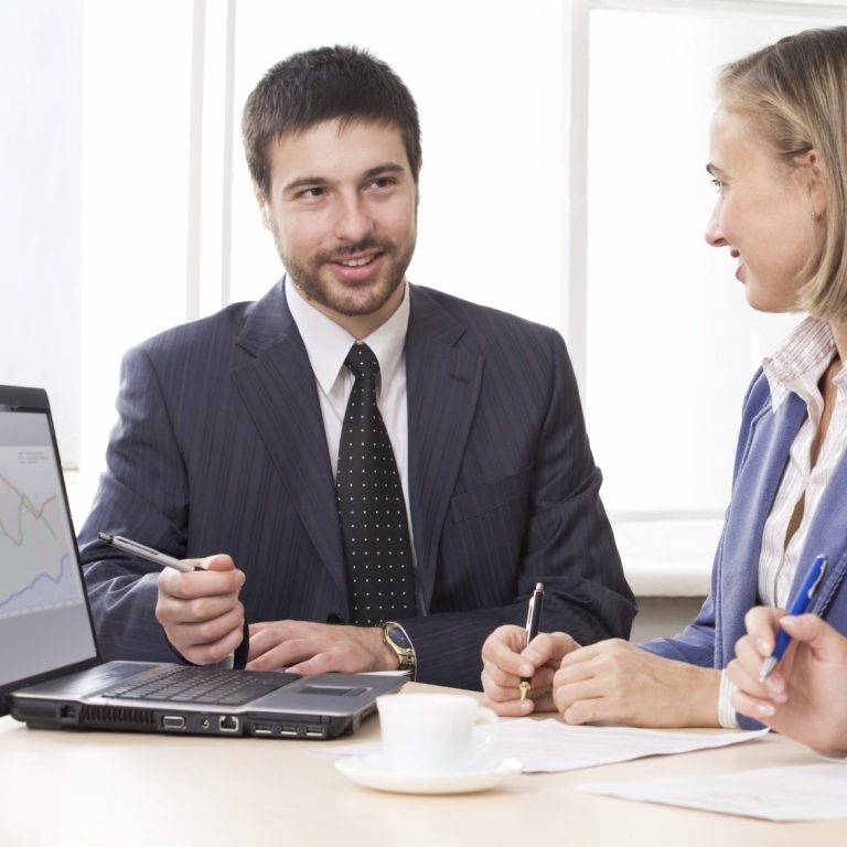 Mann und Frau in Businesskleidung diskutieren bei einem Meeting am Tisch.