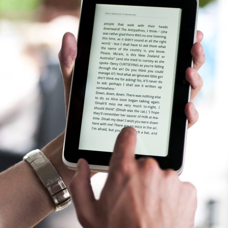 Person liest auf einem E-Reader und tippt auf den Bildschirm.
