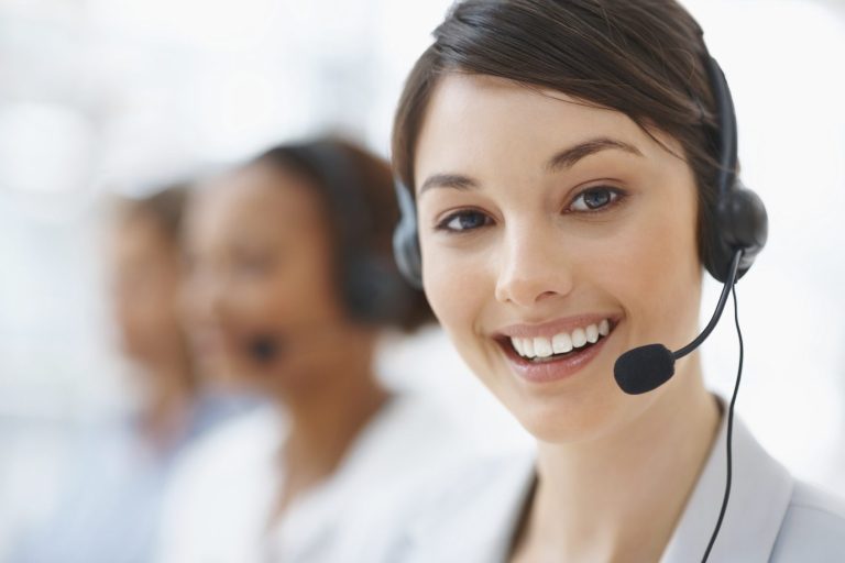 Lächelnde Frau mit Headset, in einem Kundenservice-Umfeld.