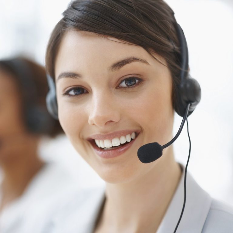 Frau mit Headset und Mikrofon, lächelnd, in einem Büro-Umfeld.