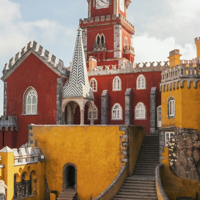 Farbenfrohes Schloss mit roten und gelben Wänden, Türmen und steinernen Treppen.