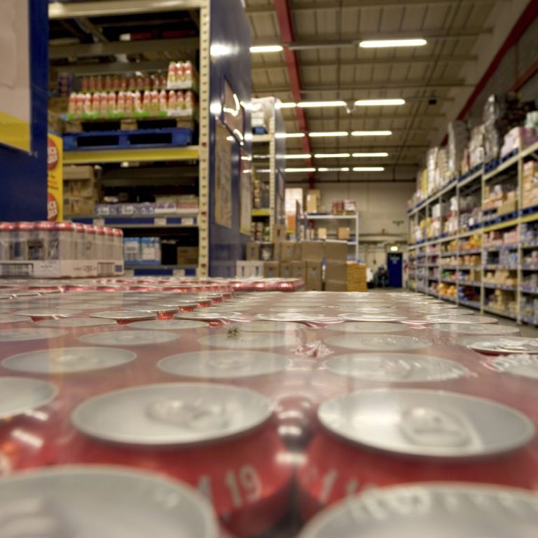 Sicht auf einen Supermarktgang mit Getränkedosen und Regalen im Hintergrund.
