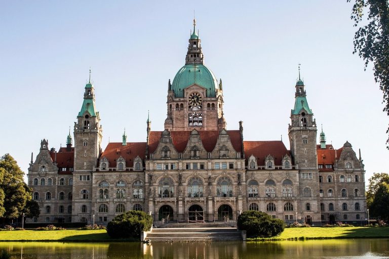 Historisches Rathaus in Hannover mit Türmen und einem großen Teich im Vordergrund.